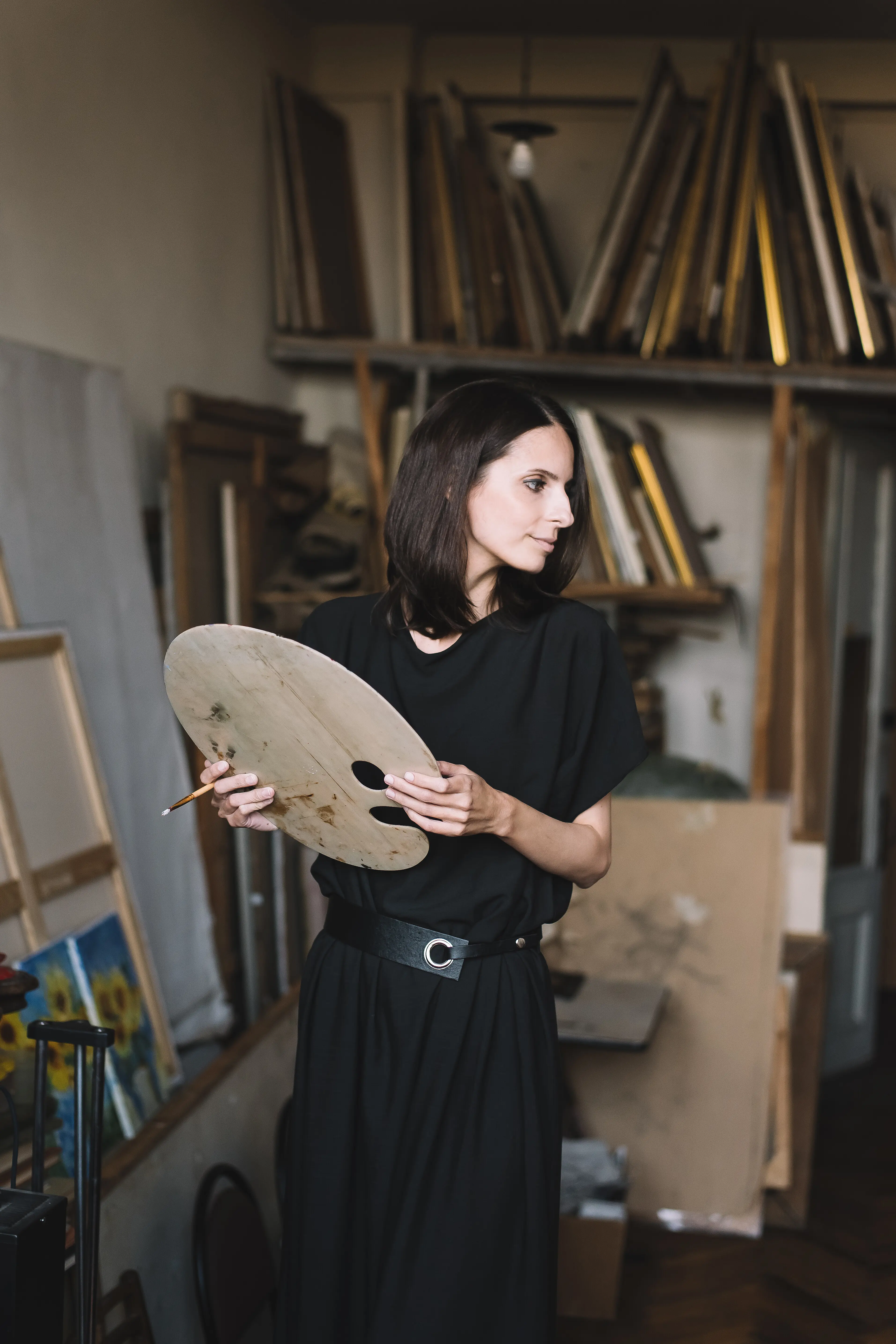 Junge Künstlerin bei der Arbeit in der Werkstatt, malt mit einem Pinsel auf einer Leinwand, Inspiration.